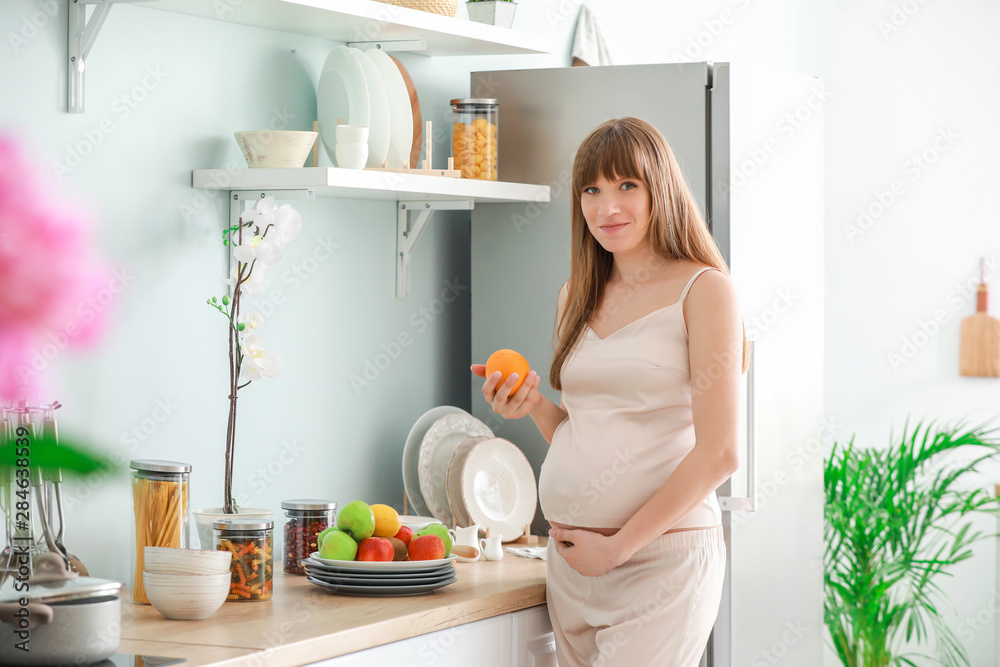 Beautiful pregnant woman with fruits in kitchen Beautiful pregnant woman with fruits in kitchen