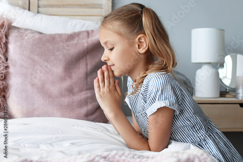 Cute little girl praying in...