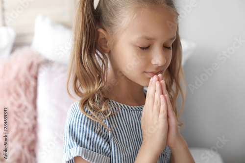 Cute little girl praying in...