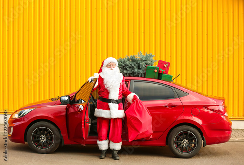 Santa Claus with gifts in bag getting out of car outdoors © Pixel-Shot