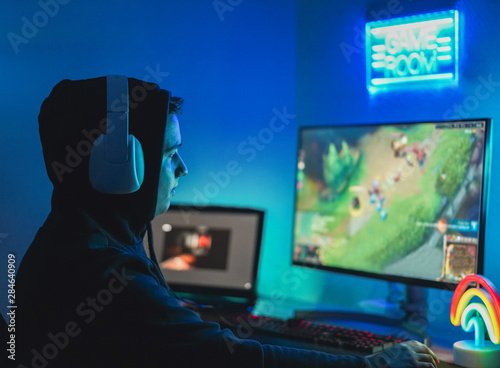 Young streamer gamer playing at strategy game in broadcast browser - Male guy having fun gaming and streaming online - New technology game trends and entertainment concept - Focus on his face photo