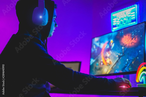 Young gamer playing at strategy online game - Male guy having fun gaming and streaming online - New technology game trends and entertainment concept - Focus on his hand