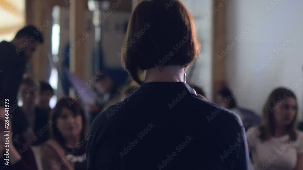 Speaker is giving speech at business event. Adult businesswoman in modern conference hall. Business and entrepreneurship seminar. Back view. Speaker is giving speech at business event. Adult businesswoman in modern conference hall. Business and entrepreneurship seminar. Back view.