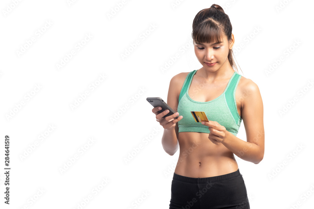 Fitness woman using mobile phone and holding credit card isolate in white background. Asian girl, looking at card. Fitness woman using mobile phone and holding credit card isolate in white background. Asian girl, looking at card.