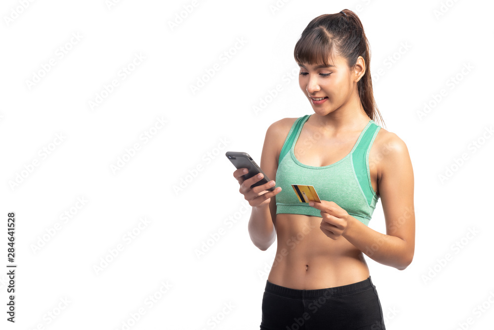 Fitness woman using mobile phone and holding credit card isolate in white background. Asian girl, looking at phone. Fitness woman using mobile phone and holding credit card isolate in white background. Asian girl, looking at phone.