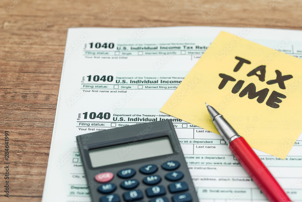 Tax Form 1040 with 'Tax time' text, calculator and pen Tax Form 1040 with 'Tax time' text, calculator and pen