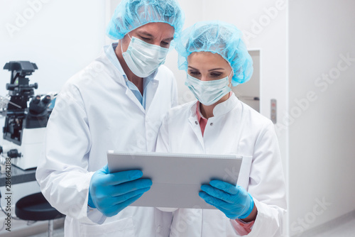 Two scientists working together in lab looking at data