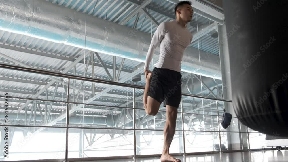 A young Asian is training in the kickboxing gym. warm up. Kickboxer athlete is actively warming up before hard training in the gym using various shells