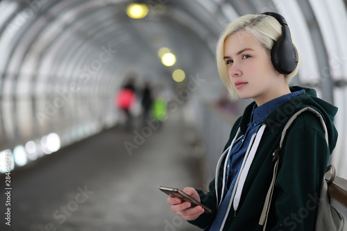 Young girl listens to music in big headphones in the subway