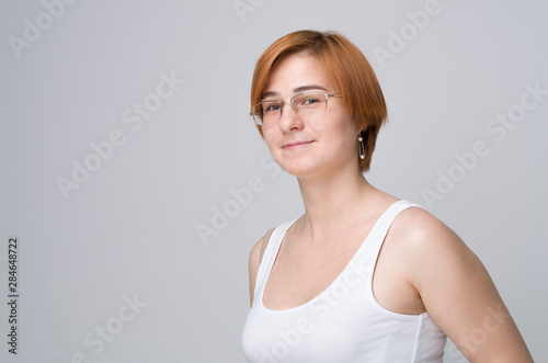 The light casual portrait of young woman with ginger hair and in glasses photo