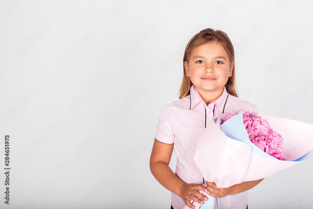 Cute adorable girl holding a bouquet of pink flowers for school teacher of lovely mom on isolated white background. Childhood, happiness, school concept Cute adorable girl holding a bouquet of pink flowers for school teacher of lovely mom on isolated white background. Childhood, happiness, school concept