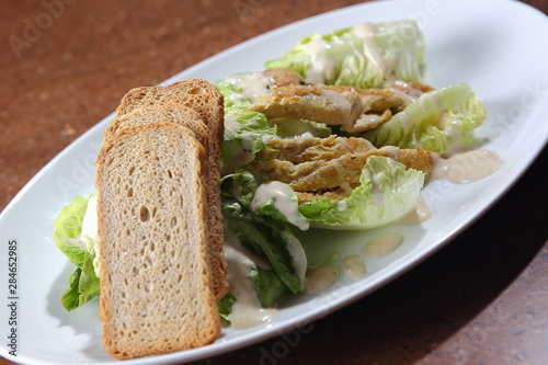 Caesar salad served with roast chicken, fresh lettuce, toasted garlic bread, Dijon mustard, Parmesan cheese and black pepper.