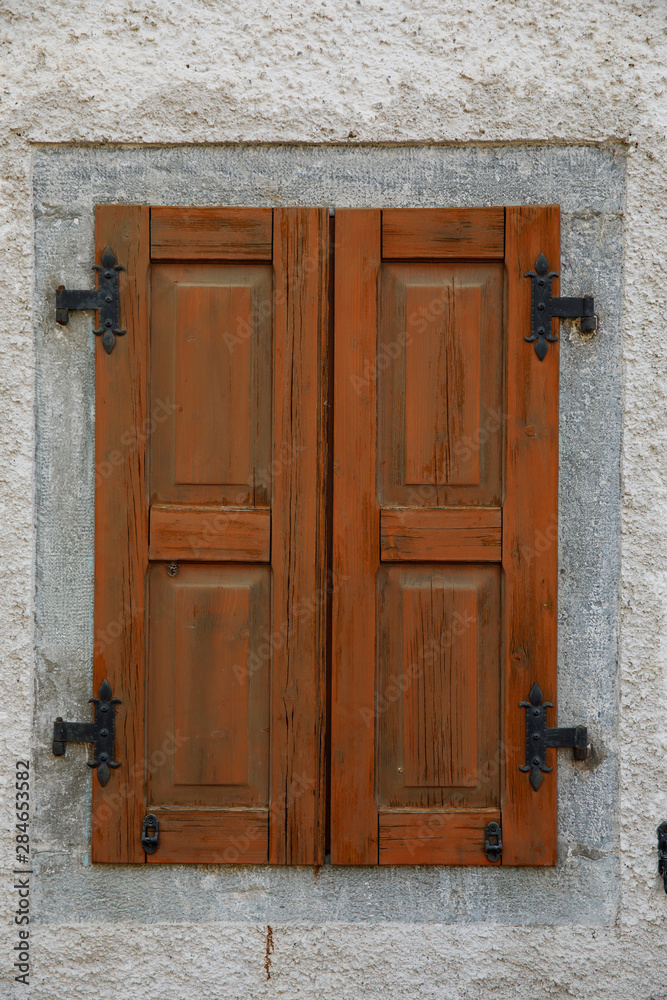 Closed brown rustic wooden window on stone wall. Closed brown rustic wooden window on stone wall.