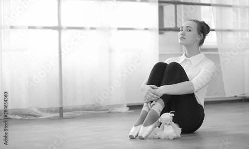 Young ballet dancer on a warm-up. The ballerina is preparing to perform in the studio. A girl in ballet clothes and shoes kneads by the handrails.