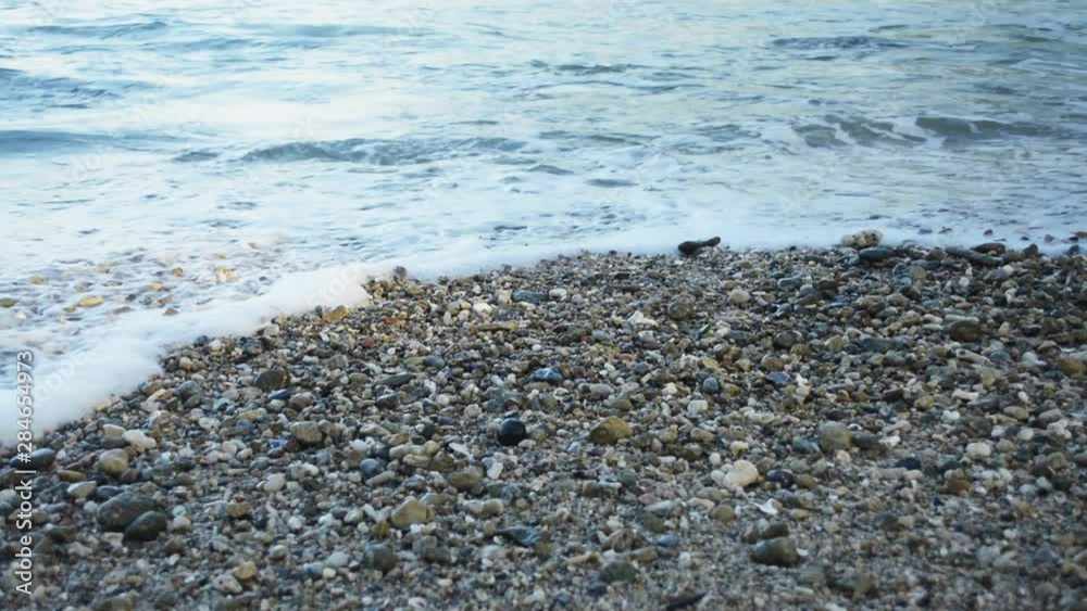 Close up of foam formed by waves breaking on a seashore with many small stone on the beach. Close up of foam formed by waves breaking on a seashore with many small stone on the beach.