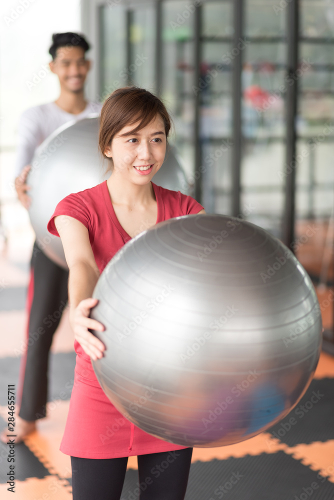 Asian women are exercises with a ball in the gym.