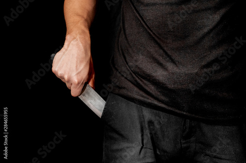 Man's hand holds a knife on black background. topics of violence and murder. thief, killer, rapist, maniac