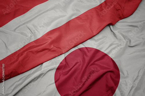 waving colorful flag of japan and national flag of austria.