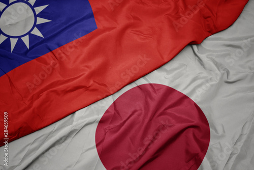 waving colorful flag of japan and national flag of taiwan.
