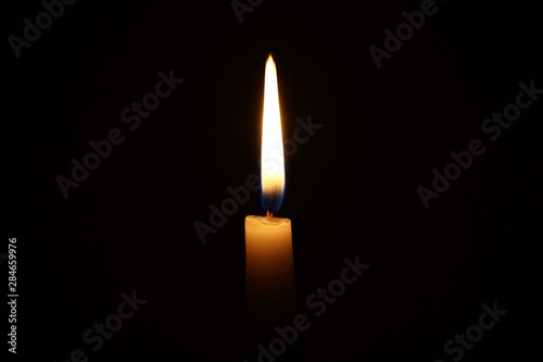 Burning candle in the dark with a dark background. Dark key photo.