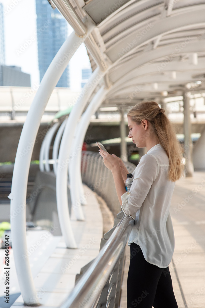 Businesswoman Using Phone On Walkway Bridge In City