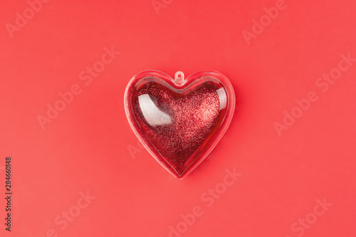 Glitter shape of  heart with female hand on red background, valentine and likes theme