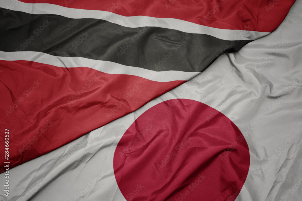waving colorful flag of japan and national flag of trinidad and tobago.