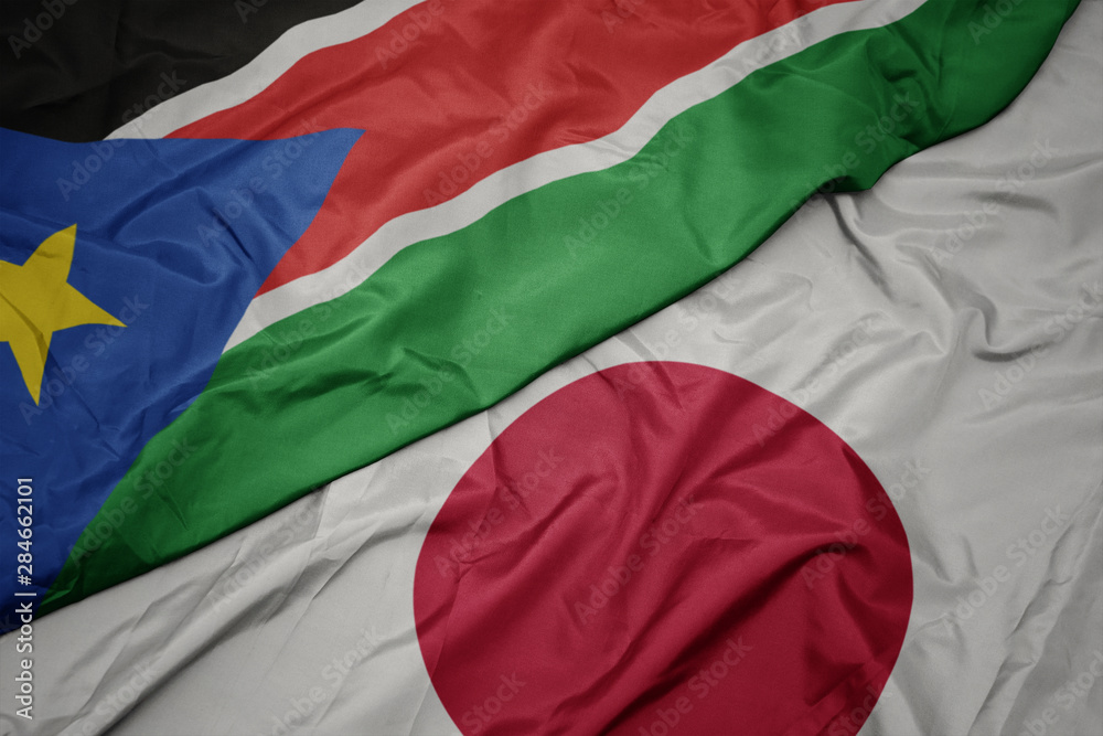 waving colorful flag of japan and national flag of south sudan.