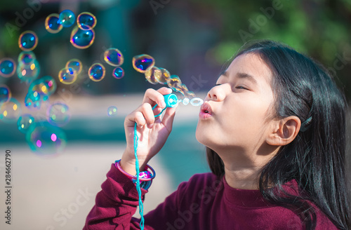 Cute little Asian girl playing soap bubbles at park  outdoors