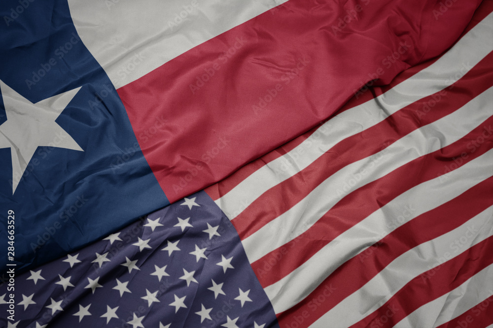 Obraz premium waving colorful flag of united states of america and flag of texas state.