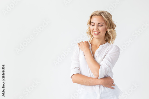 Smiling charming young blonde woman standing against a white background with copy space. Concept of carefree young girl