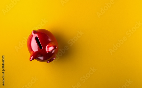 Red piggy bank on yellow background