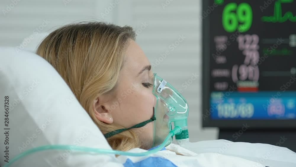 Female patient with oxygen mask lying hospital bed, emergency medicine operation Female patient with oxygen mask lying hospital bed, emergency medicine operation