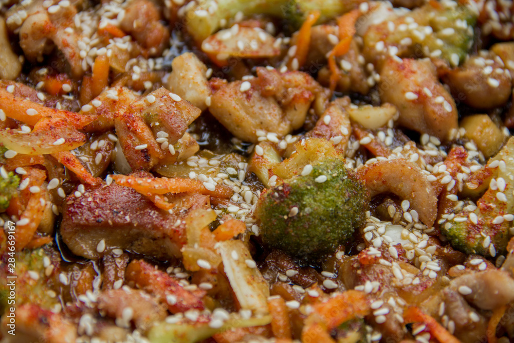 meat broccoli carrots onions garlic with sesame seeds all together in a pan. looks like a background