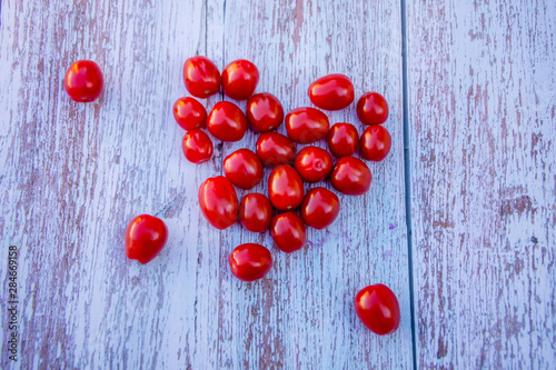 Organic ripe cherry tomatoes lined in a heart shape on a wooden table. Cooking ingredients. Harvest.