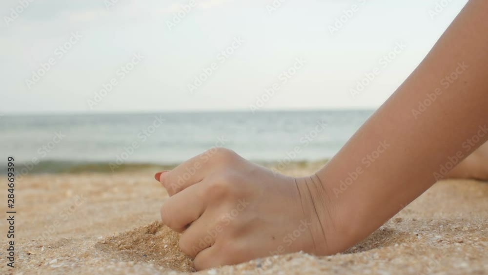 Sea shell in female hand at the beach, sand pouring down, summer day on beach and vacation relax concept Sea shell in female hand at the beach, sand pouring down, summer day on beach and vacation relax concept