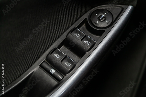 close-up of the side door buttons: window adjustment buttons, door lock. modern car interior: parts, buttons, knobs.