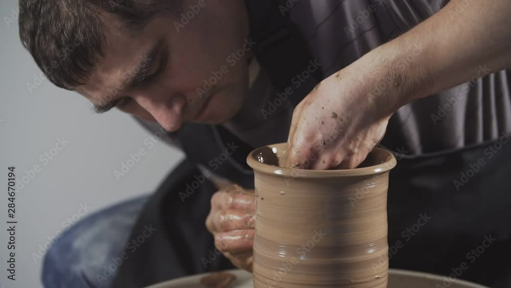 Close-up of potter working with clay on potter's wheel. Step by step. Man gently create jug from clay in slow motion. Concept of craft, handmade Close-up of potter working with clay on potter's wheel. Step by step. Man gently create jug from clay in slow motion. Concept of craft, handmade