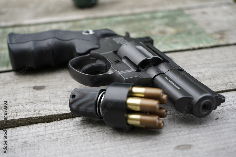Obraz premium Air gun with cartridges on a wooden background.