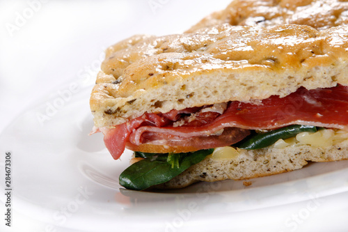 Traditional bread sandwich with serrano ham, cheese and spinach leaves.