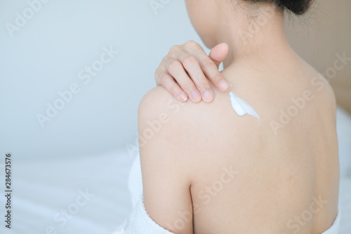 The woman is applying cream,lotion on her back., Hygiene skin body care concept.
