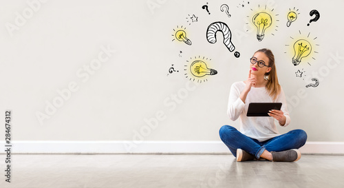 Question with light bulbs with young woman holding a tablet computer photo