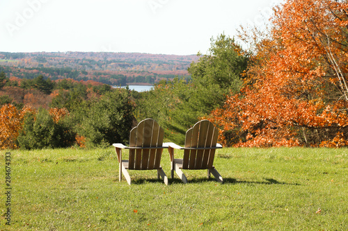 wooden adirondack chairs overlooking to a beautiful fall view of a lake and mountains