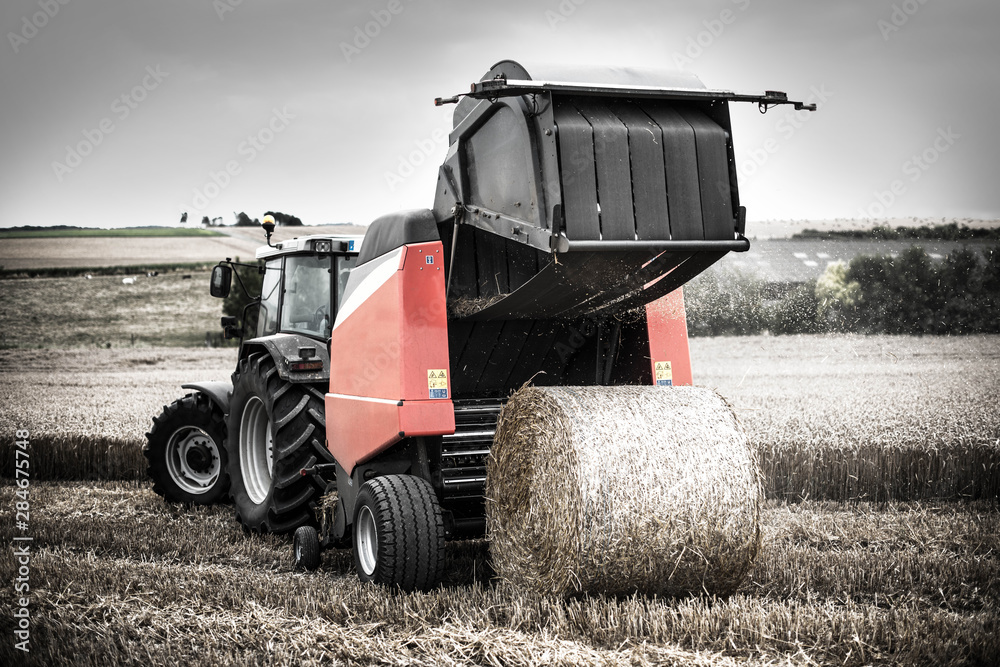 Obraz premium farmer in fields making straw bales