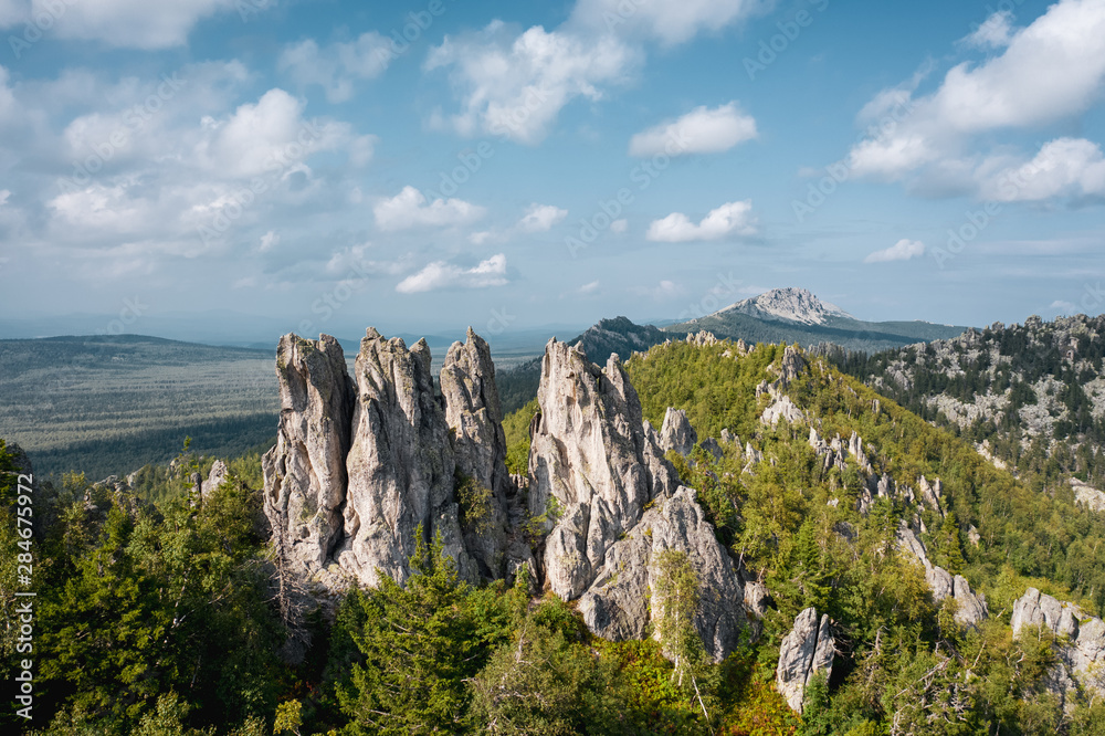 aerial view of russian national park Taganay. drone flying down near steep stony slope of mount overgrown with deep taiga forest of oldest mountain range in the world. beautiful scenery of wild nature