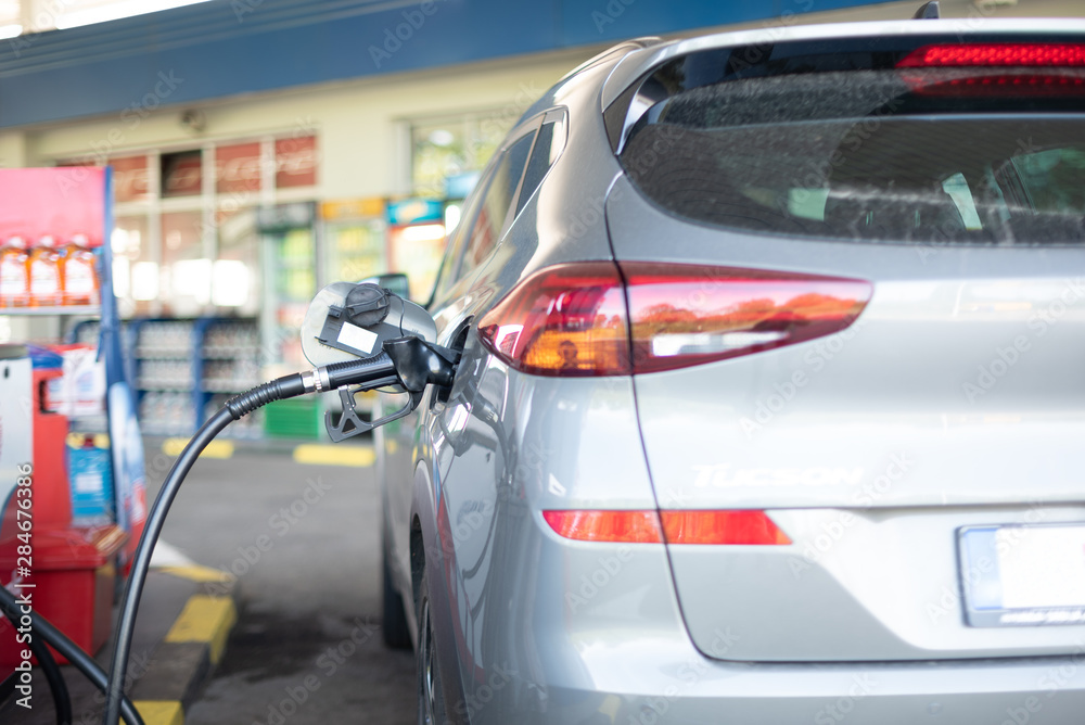 Refueling refilling car vehicle with fuel at refuel fuel gas pump station - Petrol diesel gas pump gun in the tank to fill - Transportation and ownership concept of vehicle fuel cost price