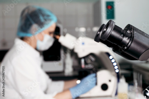 Fototapeta Naklejka Na Ścianę i Meble -  Scientist woman looking through microscope in laboratory Microscope in laboratory, analyzes.