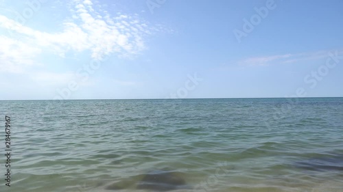 Sea view on the nice summer day: blue sky with small clouds, clean blue water.
