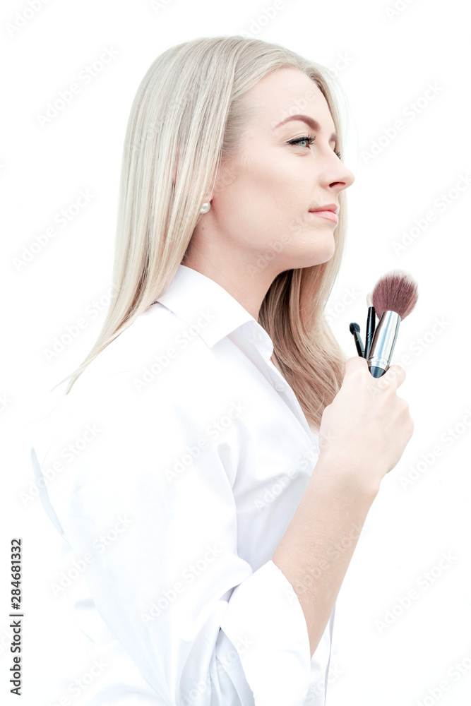 Beautiful girl in white shirt holds makeup brushes in hands. Concept make-up artist, beauty, makeup. Vertical photo. Beautiful girl in white shirt holds makeup brushes in hands. Concept make-up artist, beauty, makeup. Vertical photo.