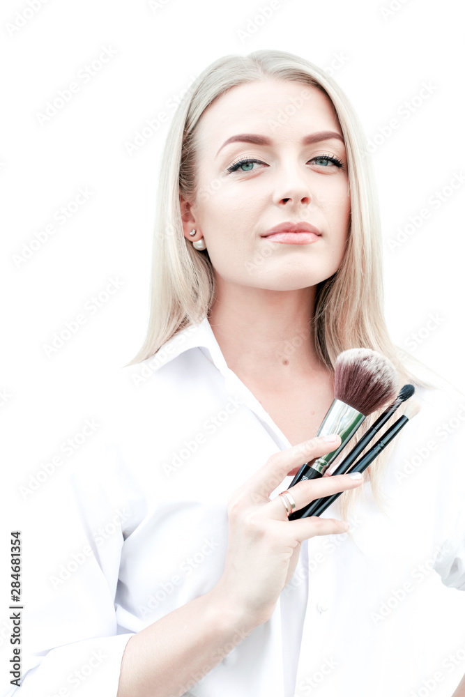 Beautiful girl in white shirt holds makeup brushes in hands. Concept make-up artist, beauty, makeup. Vertical photo. Beautiful girl in white shirt holds makeup brushes in hands. Concept make-up artist, beauty, makeup. Vertical photo.